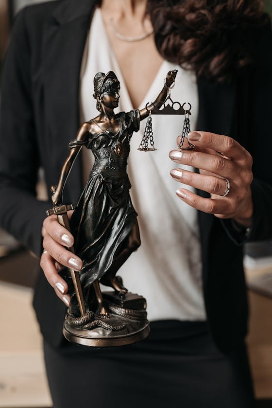 Person Holding a Statuette of Lady Justice